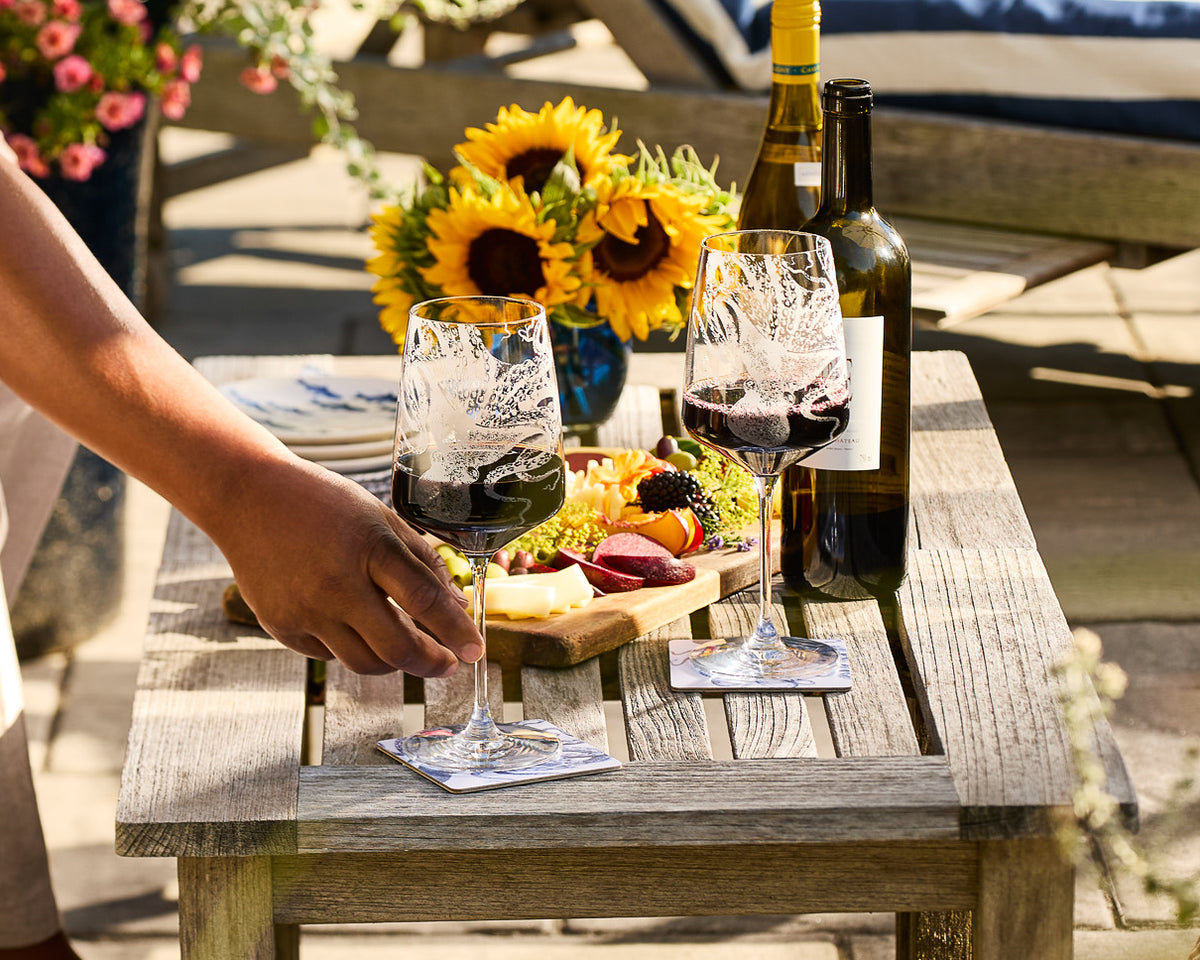 Caskata Crystal etched Lucy the Octopus red wine glasses on a table with charcuterie outdoors