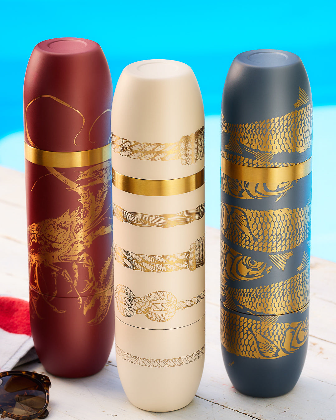 Caskata x High Camp Wine Flasks in three colors: Rosso (red) with gold lobsters engraved, Crema (creamy white) with gold sailors knots engraved, and Amalfi (navy) Blue with Sardines engraved in gold.