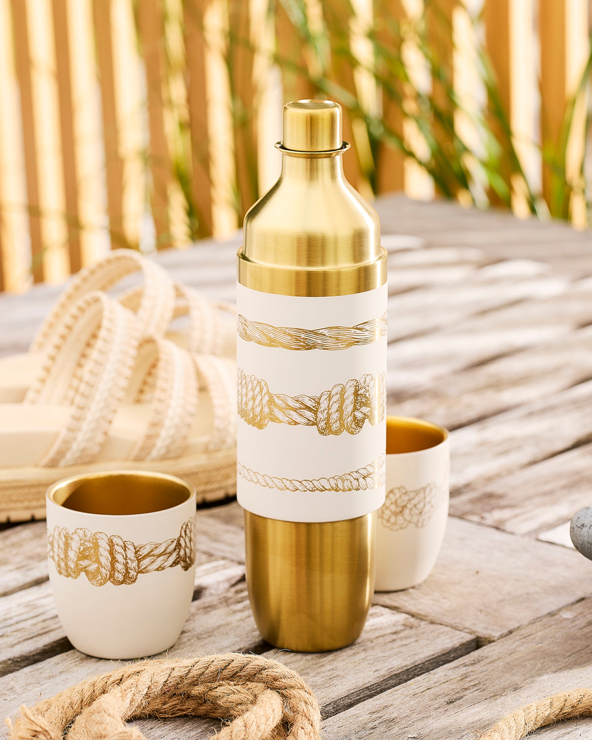 Caskata x High Camp Wine Flask in Crema with gold engraving of the Sailors Knots pattern on a dock in the sunshine.