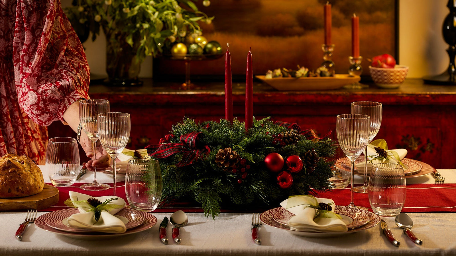 Holiday table set with Caskata holiday plates, candles, and greenery for a cozy Christmas dinner