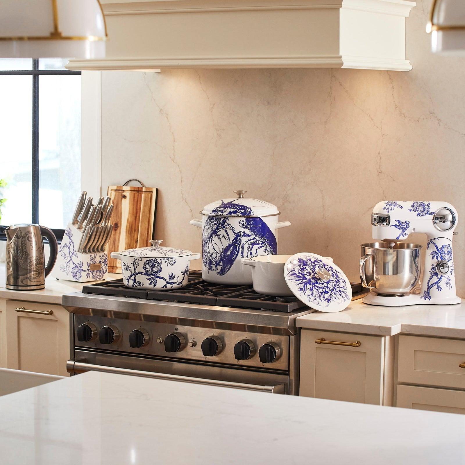 A kitchen with a stove and countertop featuring various blue and white floral patterned cookware and appliances, including pots, a mixer, and a teapot.