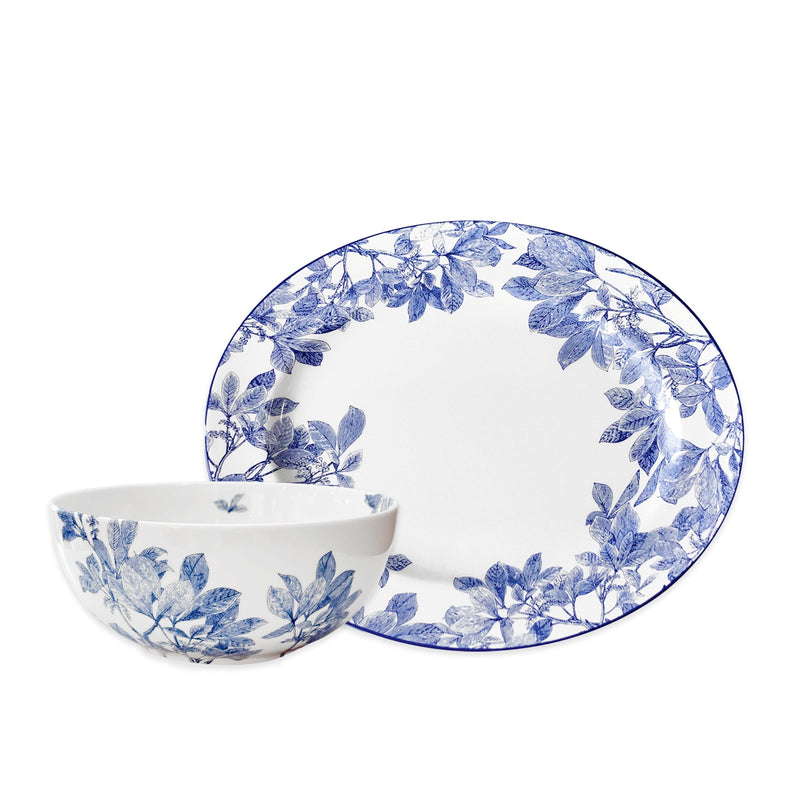 The Caskata Arbor Serving Set includes a white porcelain vegetable bowl and large oval platter, both featuring elegant blue leaf patterns along the edges.