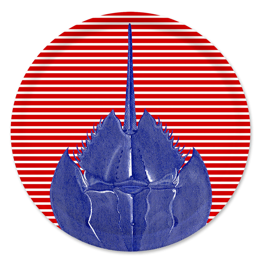 The Caskata Horseshoe Crab Large Round Birchwood Tray features a blue horseshoe crab on a red and white striped circular background, echoing vibrant Finnish design.