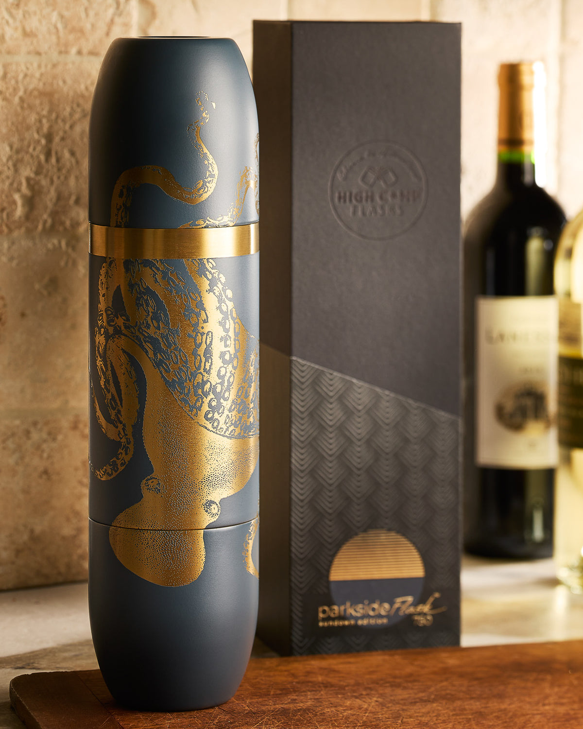 Caskata X High Camp WIne Flask with and engraving of Lucy The Ocopus in Gold on Amalfi Blue (navy) on a counter with its box.
