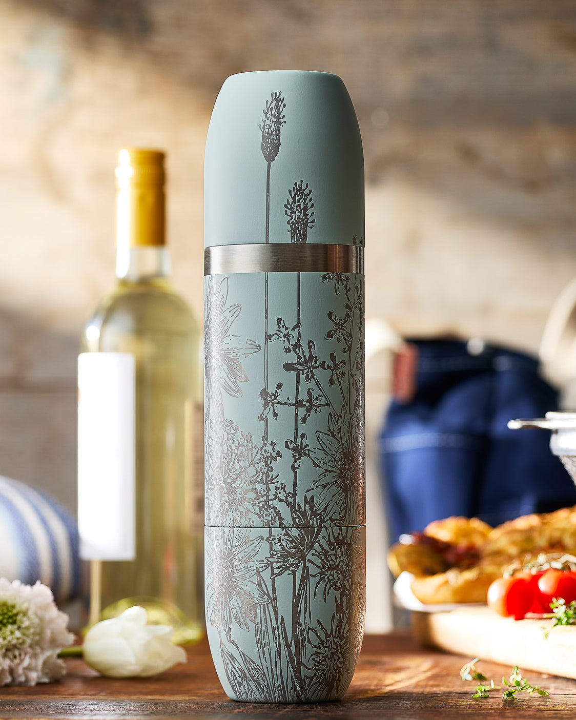 Caskata x High Camp Summer Wine Flask in Granite (light blue) on a kitchen counter with a wine bottle in the background