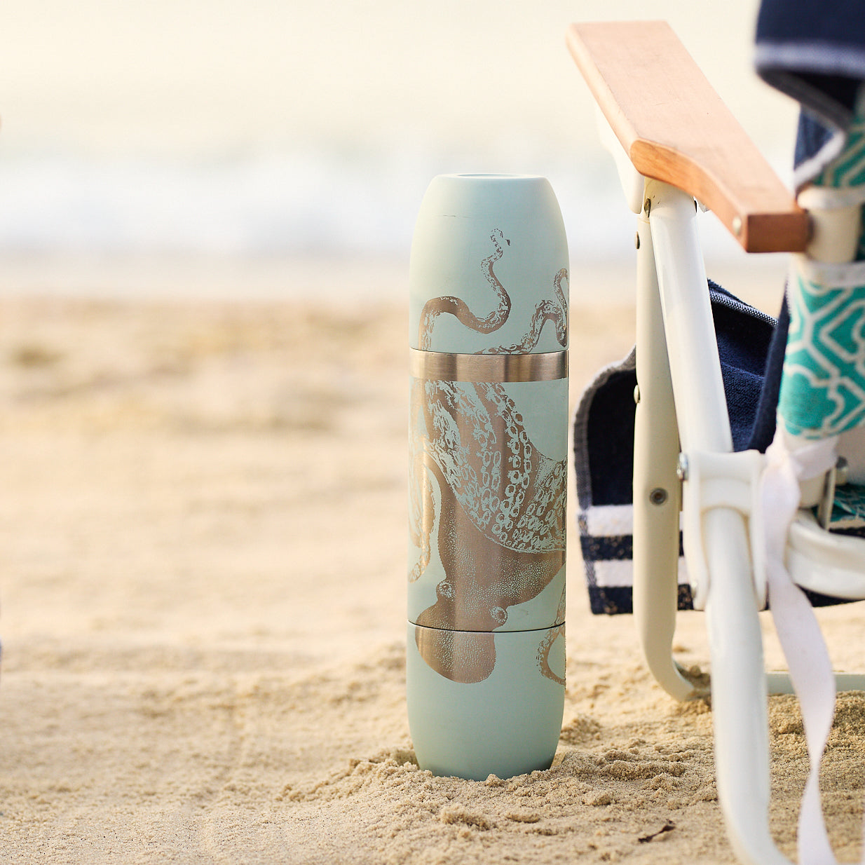 The Caskata x High Camp Light Blue Lucy Wine Flask features an illustrated octopus on a light blue flask, shown upright next to its box—perfect for outdoor adventures. Brand: Caskata.