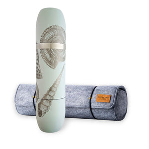 A Caskata x High Camp Light Blue Shells Wine Flask and Case Bundle stands upright next to a rolled-up gray felt carrying case with a brown leather label, the shell patterns on the flask perfectly matching your yoga mat for the ideal post-session refreshment.