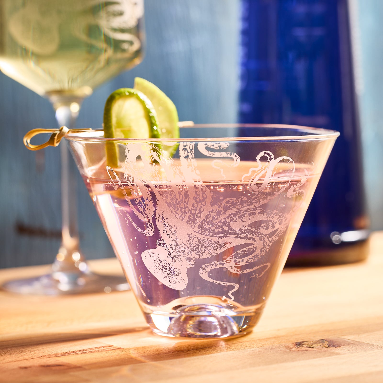 Two Lucy Stemless Martini Glasses by Caskata Artisanal Home, crafted from lead-free crystal with etched octopus designs, are shown side by side on a white background.