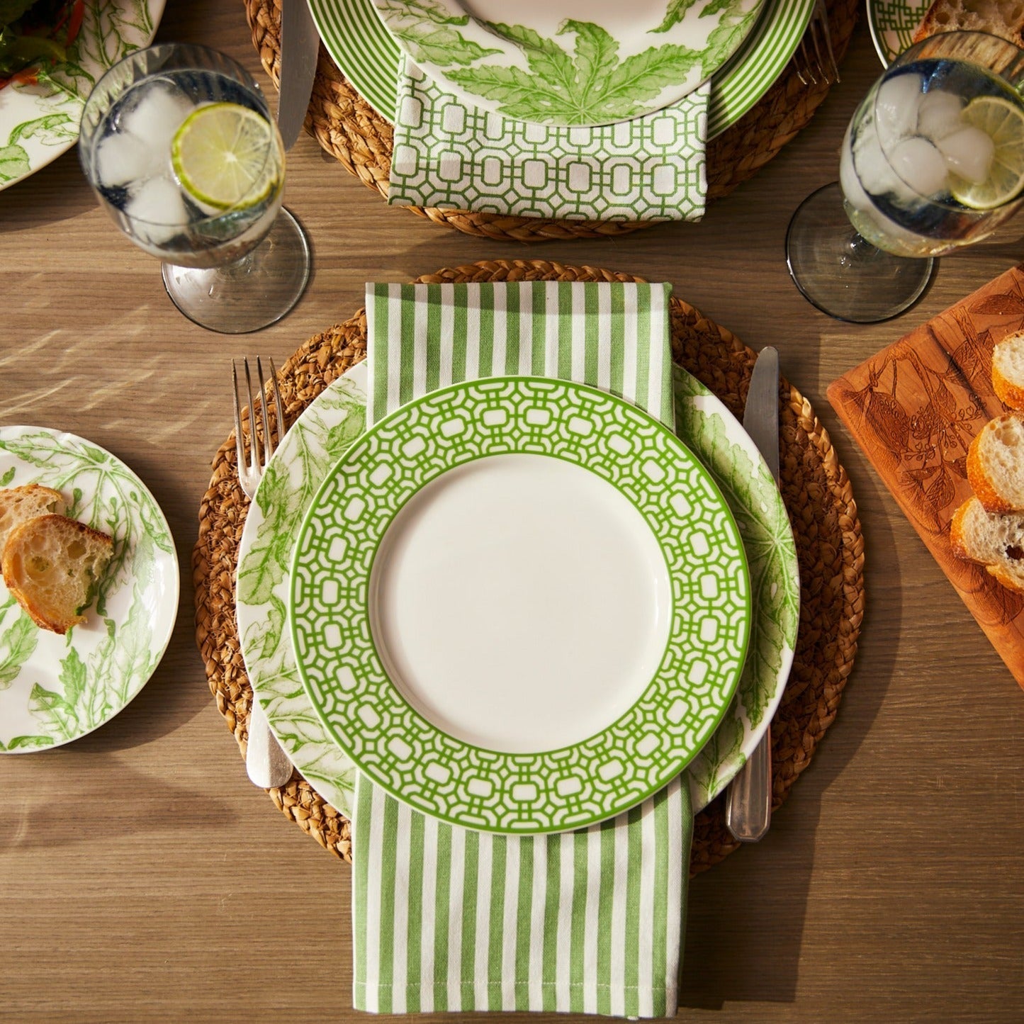 Four Caskata Pinstripe Dinner Napkins in spring green cotton with white vertical stripes are laid flat and slightly overlapping on a white background.