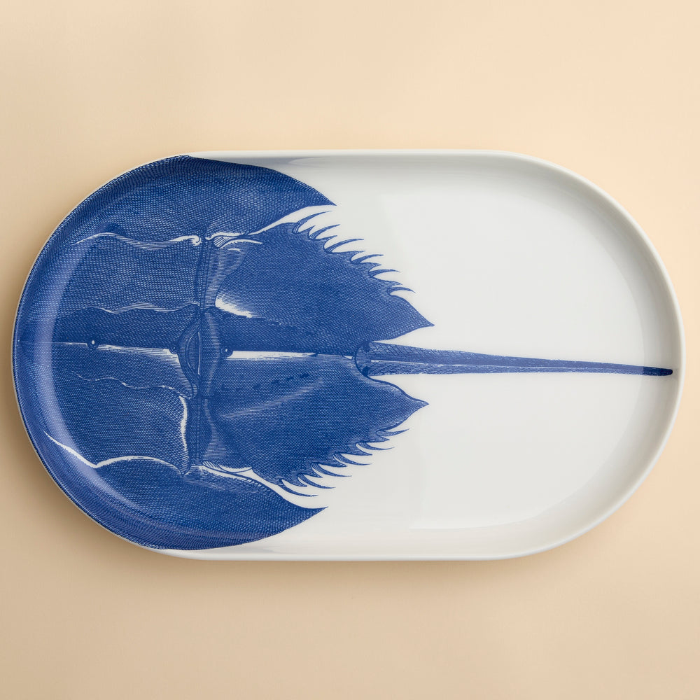 A highly detailed engraving of a horseshoe Crab in brilliant blue adorns this large oval platter from Caskata in premium porcelain, 