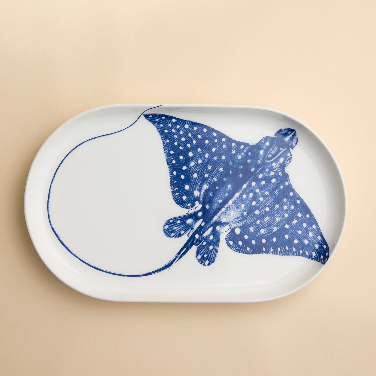 Ray the Stingray floats across this large coupe oval serving platter in blue and white on high-fired porcelain from Caskata