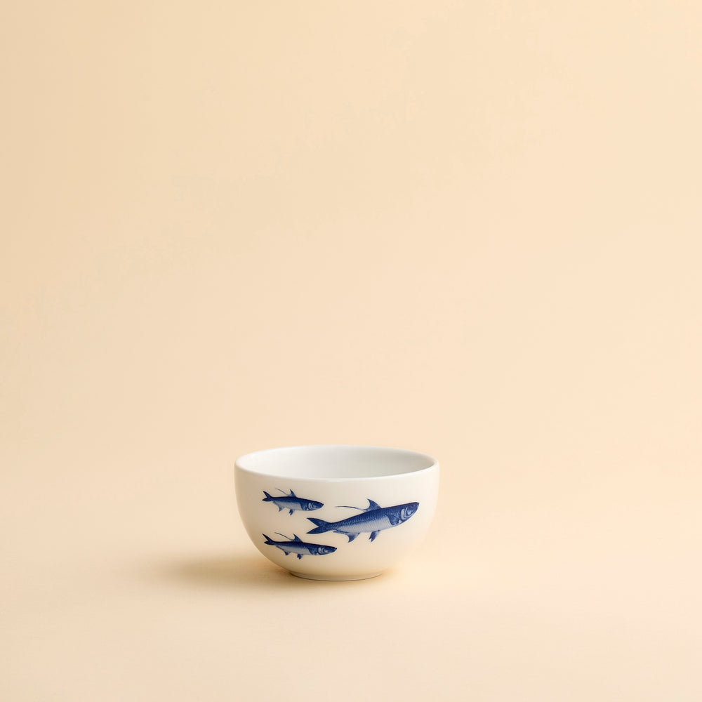 An adorable snack bowl in high-fired porcelain features a bright blue School of Fish swimming around and inside this hand-decorated porcelain bowl from Caskata.