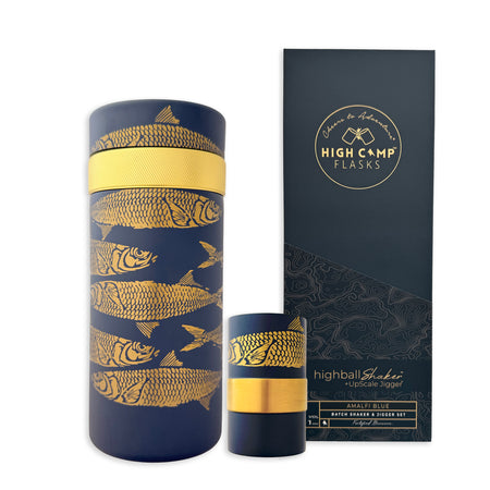The Caskata x High Camp Sardines Batch Cocktail Shaker by Caskata features blue barware with gold fish designs and comes in stylish black and gold packaging—an eye-catching essential for any home bar collection.