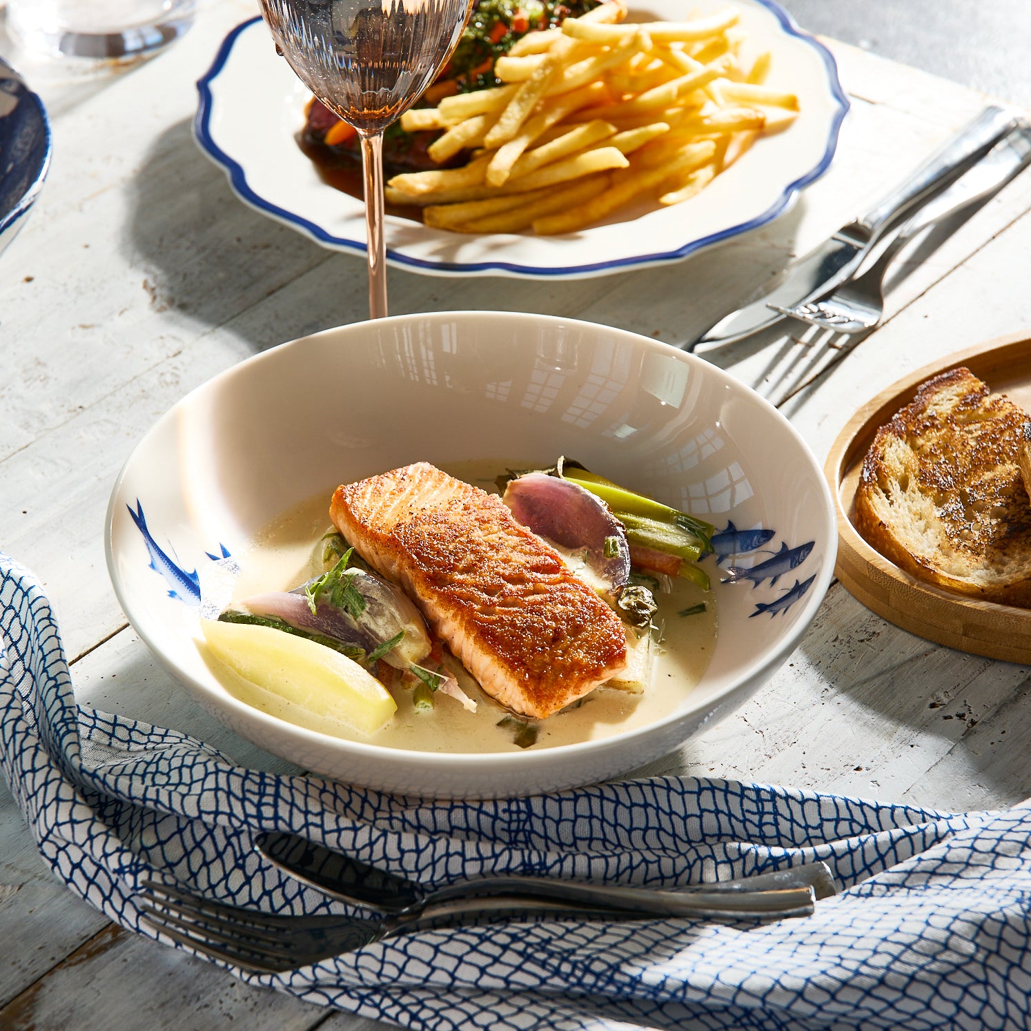 Mixed set of 4 Coastal Creatures in the Mixed Coastal Icon Entree Bowl Set from Caskata. In Blue on creamy white porcelain, including School of Fish, Lobster, Crab, and Lucy the octopus.
