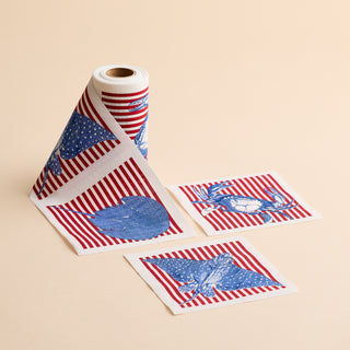 The Seaside Stripes Cocktail Napkin Roll by MY DRAP features a roll of patterned napkins adorned with red stripes alongside blue eagle, heart, and deer motifs, reminiscent of coastal charm; two individual sheets are displayed flat on a beige background.