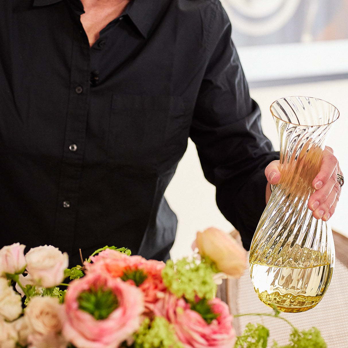 The Quinn Citrine Dinner Party Set by Caskata features a clear glass carafe with a swirl pattern and six matching stemless crystal glasses, all tinted a soft yellow—an elegant addition to any table.