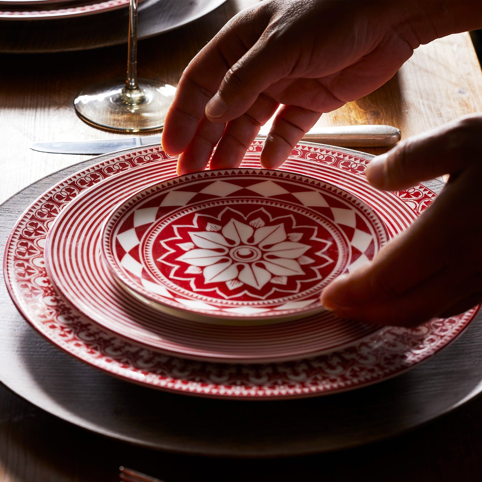 A Newport Crimson Stripe Salad with concentric rings of red stripes around the rim of this high-fired porcelain plate from Caskata, shown against a creamy beige background.