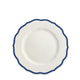 A top-view of the Stella Scalloped Blue Salad Plate by Caskata, featuring white porcelain with a scalloped edge and dark blue trim, evokes the charm of vintage dinnerware.