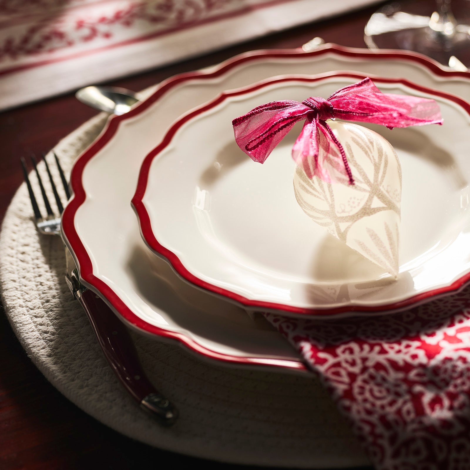 The Stella Red Table for 8 by Caskata offers twelve white plates with red scalloped edges and two bowls with red geometric patterns—an ideal porcelain dinnerware set to create a festive holiday look for special gatherings.