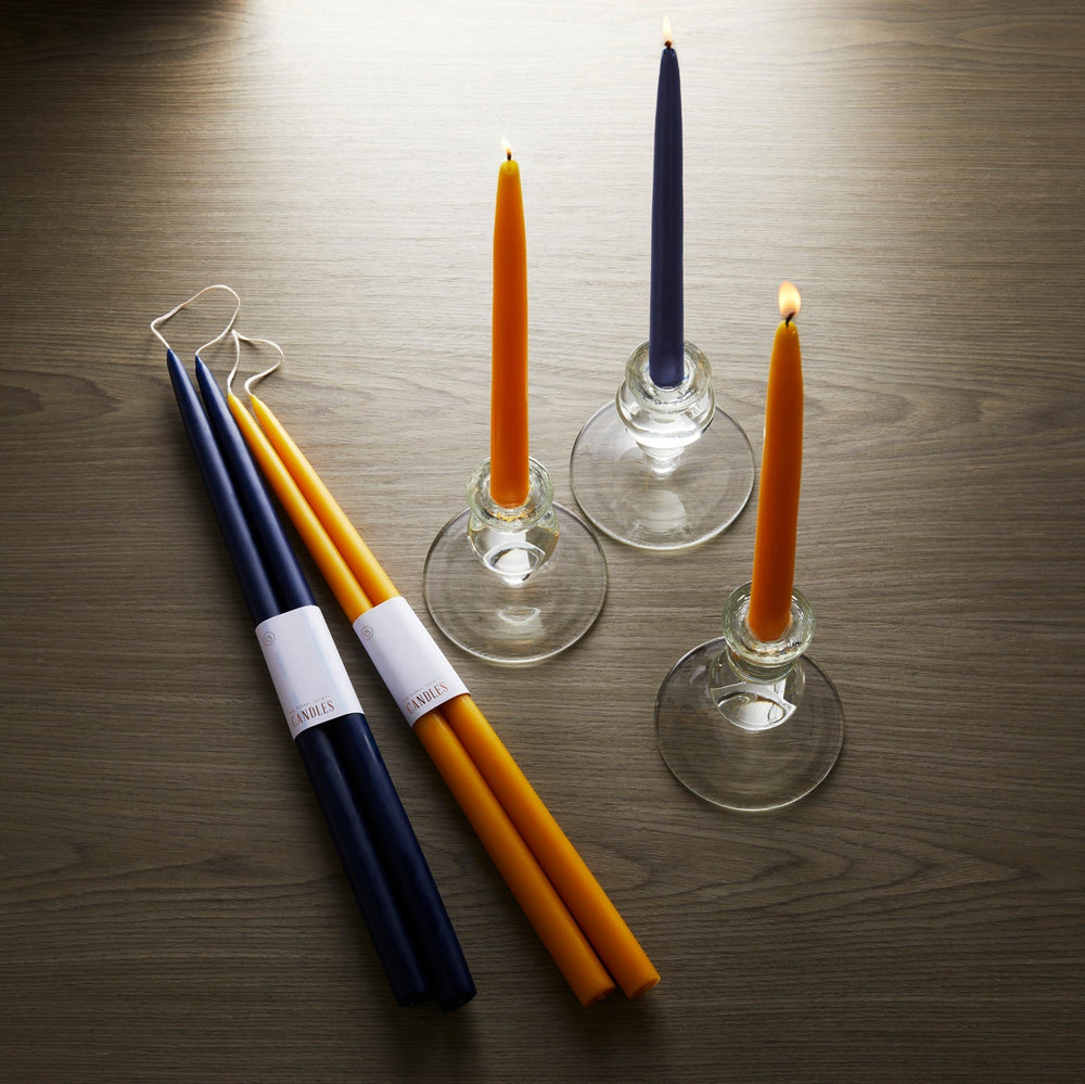 Three 18" Marigold Taper Candles - Set of 2 by Floral Society are sitting on a table in a summer setting.