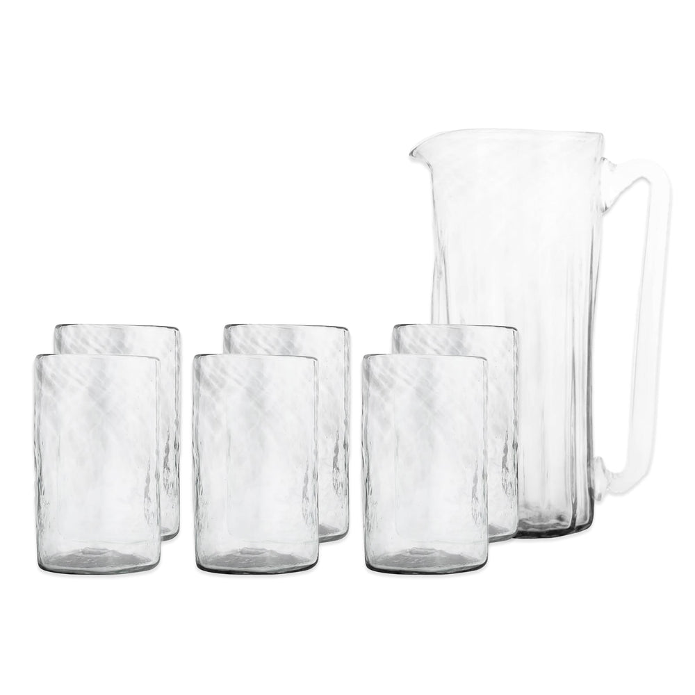 The Viento Essentials Serving Bundle by Caskata features a clear handblown glass pitcher with handle and six matching glass tumblers, shown on a plain white background.