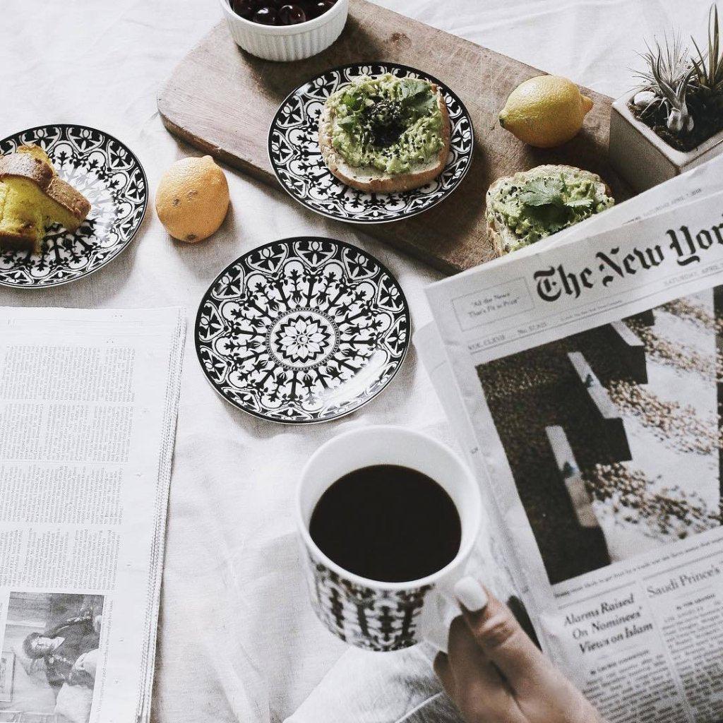 Four round, black porcelain plates with intricate white floral and geometric patterns, arranged in a slightly overlapping layout, against a white background. These heirloom-quality Casablanca Small Plates from Caskata Artisanal Home are as stylish as they are timeless.